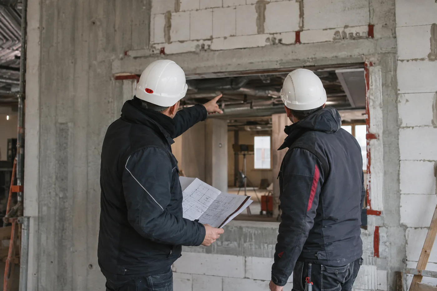 Zwei Fachkräfte begutachten gemeinsam eine Wandöffnung im Rohbau